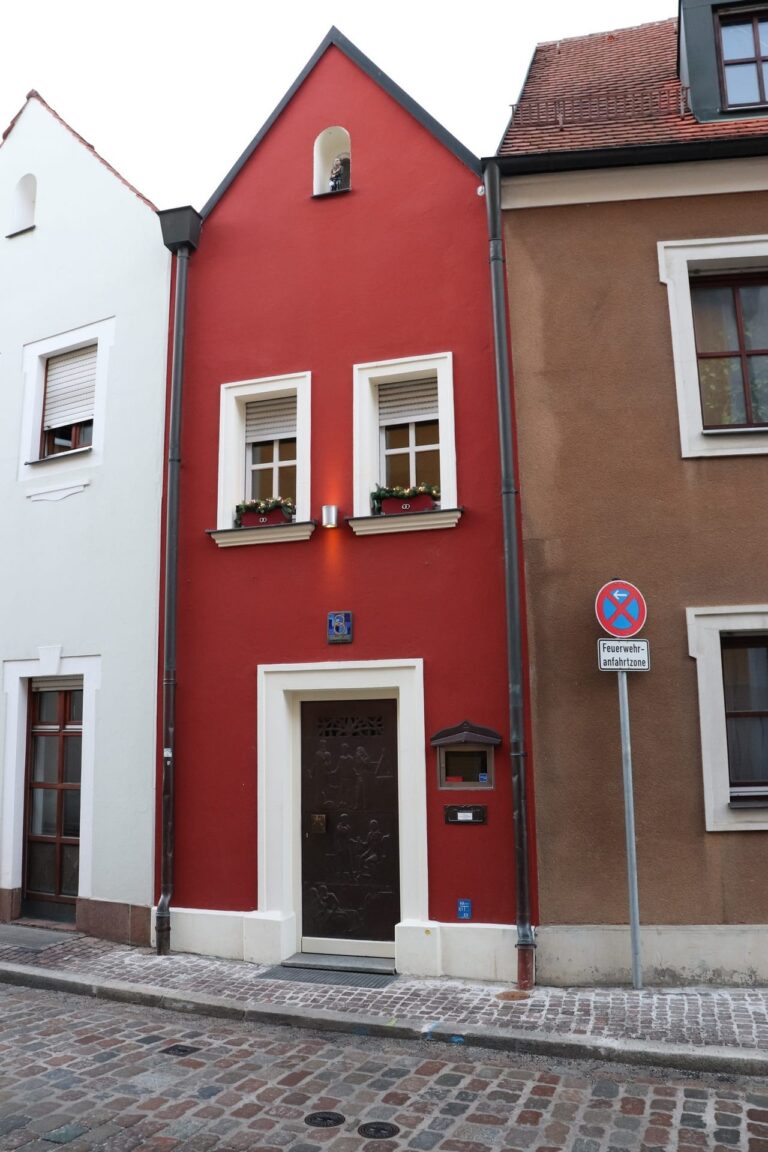 Das Eh`Häusl in Amberg ist das kleinste Hotel der Welt und ist weinrot gestrichen mit zwei Fenstern und einer blauen Hausnummer aus Keramik.