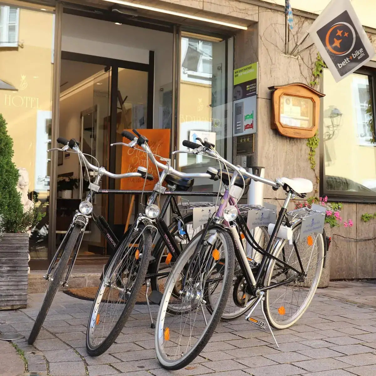Drei Fahrräder vor dem Hotel Brunner in Amberg. Im Hintergrund sieht man eine Bett & Bike Fahne.