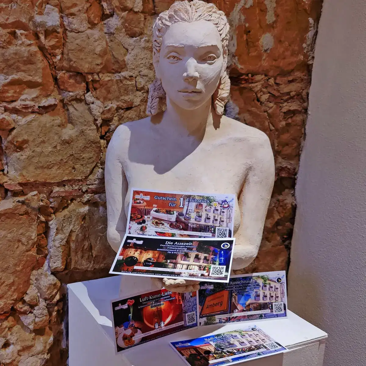 Präsentation der Gutscheine des Hotel Brunner an einer Frauen-Statue aus Gips von Lilian Kovács.