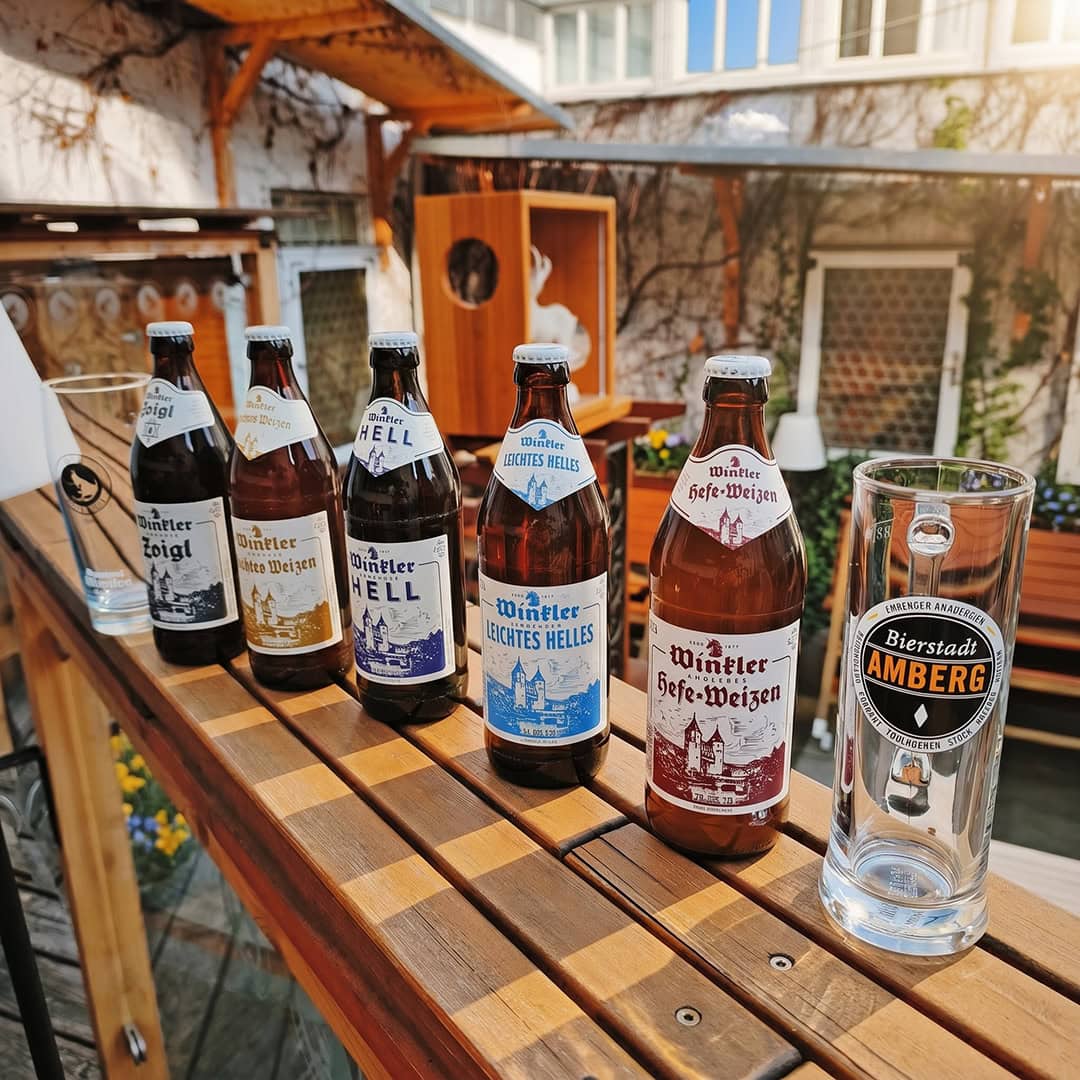 Teaserbild für unser Angebot zum Amberger Bierfest 2026 mit einer Reihe Winkler Bierflaschen sowie den offiziellen Amberger Bierkrug